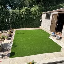 After 6 A tidy garden space with artificial grass and a shed surrounded by plants.