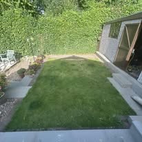 before 6 A well-maintained garden with grass, a shed, and patio furniture.