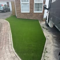 After 5 Lush green artificial grass bordered by brick paving and a truck.