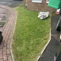 Before 5 Well-maintained lawn with a pile of fabric and a brick pavement nearby.