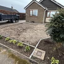 Before 2 A brown brick house with a gravel front garden and newly planted greenery.